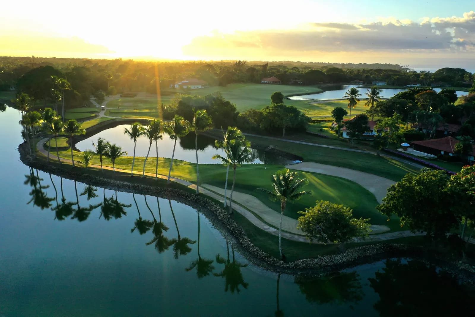 Sunrise aerial of a palm-ringed lakeside green at The Links, Casa de Campo