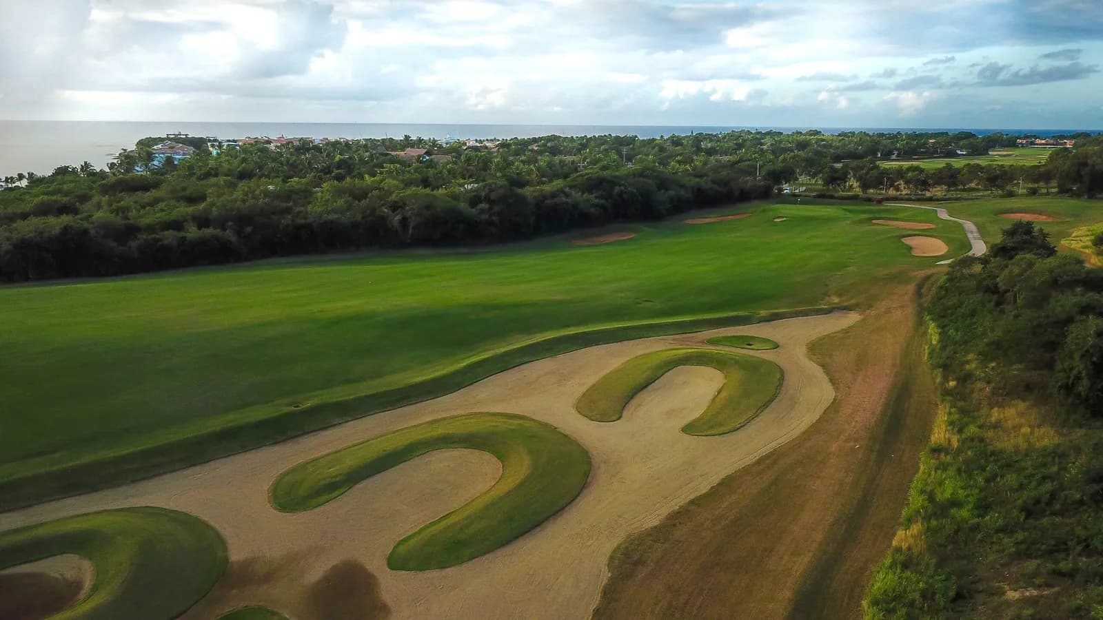 Aerial of a Dye Fore fairway lined with horseshoe waste bunkers, marina and sea beyond