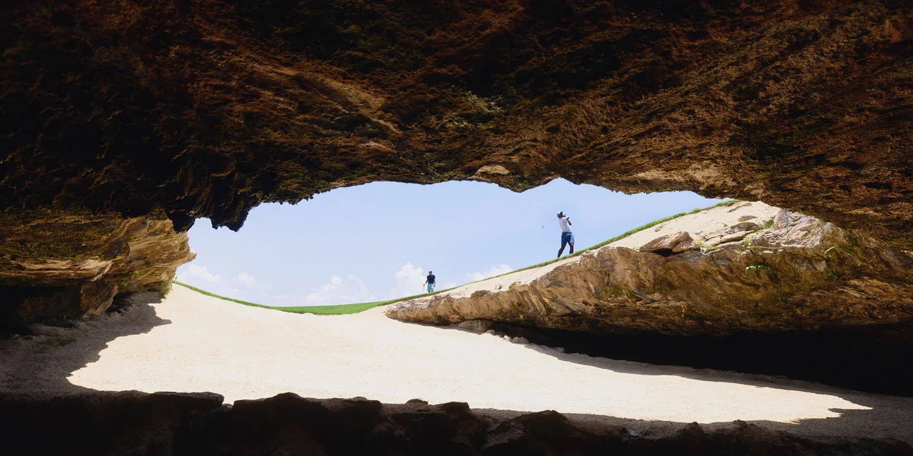Golfers on the fairway seen from inside the cenote cave at El Camaleón, Mayakoba