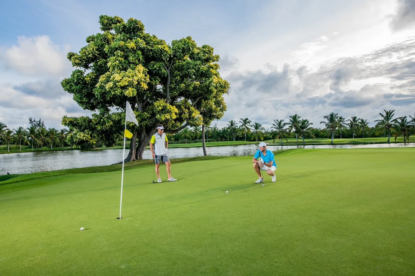 Two golfers reading a putt on a lakeside green at The Lakes Barceló